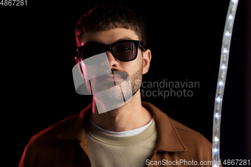 Image of man in sunglasses over neon lights at nightclub