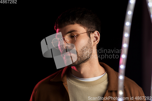 Image of man in glasses over neon lights at nightclub