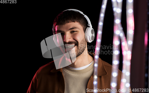 Image of man in headphones over neon lights of night club