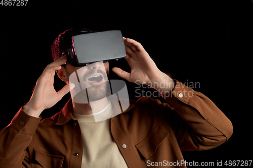 Image of surprised man in vr glasses over black background