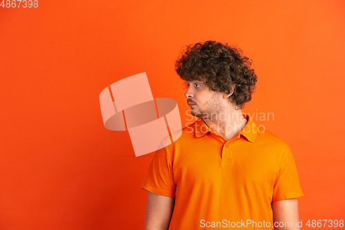 Image of Caucasian young man\'s monochrome portrait on orange studio background