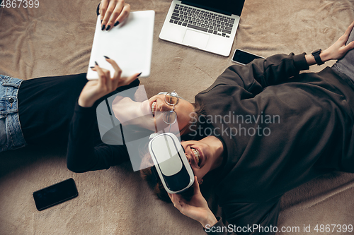 Image of Attractive young couple using devices together, tablet, laptop, smartphone, headphones wireless. Gadgets and technologies connecting people all around the world