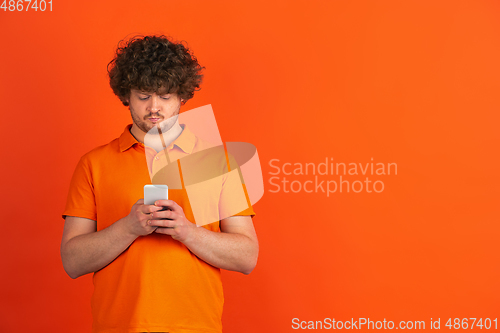 Image of Caucasian young man\'s monochrome portrait on orange studio background