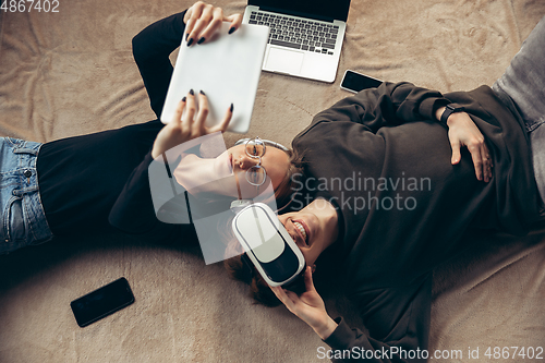 Image of Attractive young couple using devices together, tablet, laptop, smartphone, headphones wireless. Gadgets and technologies connecting people all around the world. Top view