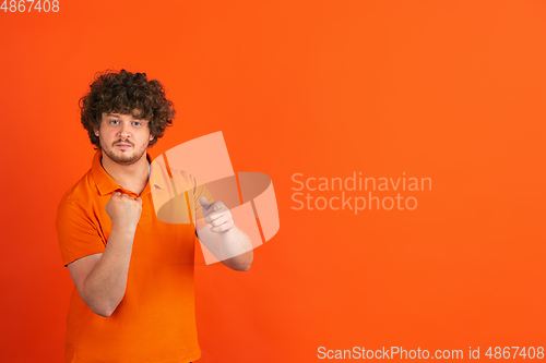 Image of Caucasian young man\'s monochrome portrait on orange studio background