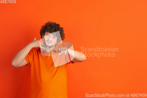 Image of Caucasian young man\'s monochrome portrait on orange studio background