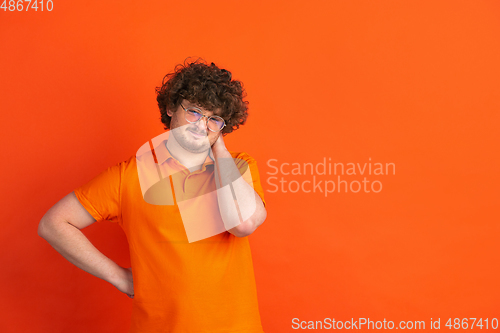 Image of Caucasian young man\'s monochrome portrait on orange studio background