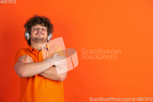 Image of Caucasian young man\'s monochrome portrait on orange studio background
