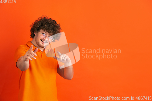 Image of Caucasian young man\'s monochrome portrait on orange studio background