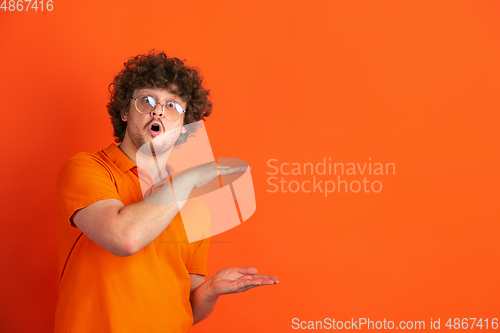 Image of Caucasian young man\'s monochrome portrait on orange studio background