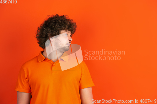 Image of Caucasian young man\'s monochrome portrait on orange studio background