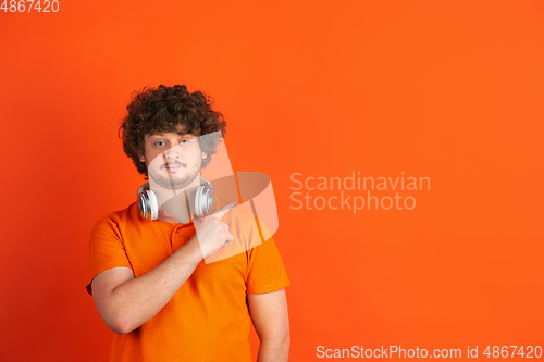 Image of Caucasian young man\'s monochrome portrait on orange studio background