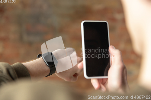 Image of Close up of male hands using smartphone and smartwatch, education and business concept, blank screen