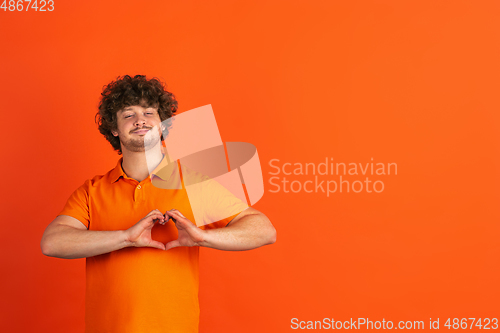 Image of Caucasian young man\'s monochrome portrait on orange studio background