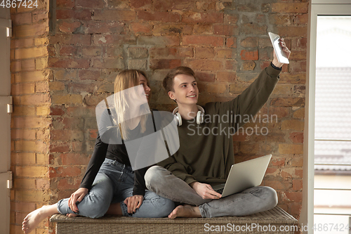 Image of Attractive young couple using devices together, tablet, laptop, smartphone, headphones wireless. Gadgets and technologies connecting people all around the world