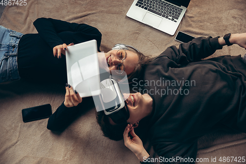 Image of Attractive young couple using devices together, tablet, laptop, smartphone, headphones wireless. Gadgets and technologies connecting people all around the world