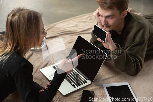 Image of Attractive young couple using devices together, tablet, laptop, smartphone, headphones wireless. Gadgets and technologies connecting people all around the world