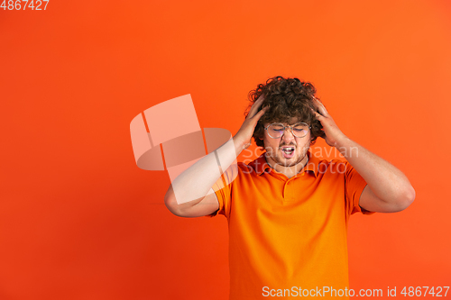 Image of Caucasian young man\'s monochrome portrait on orange studio background