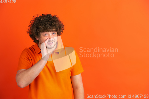 Image of Caucasian young man\'s monochrome portrait on orange studio background