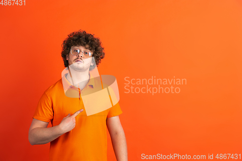 Image of Caucasian young man\'s monochrome portrait on orange studio background