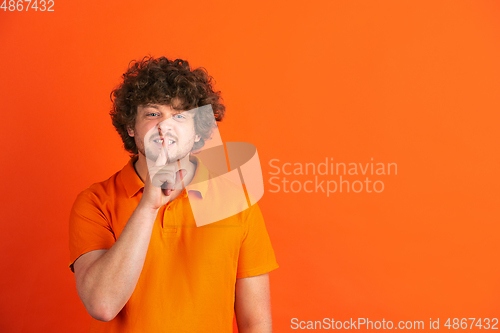 Image of Caucasian young man\'s monochrome portrait on orange studio background