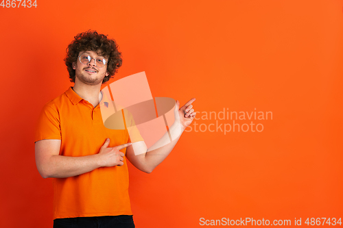 Image of Caucasian young man\'s monochrome portrait on orange studio background