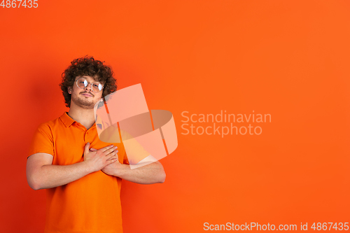 Image of Caucasian young man\'s monochrome portrait on orange studio background