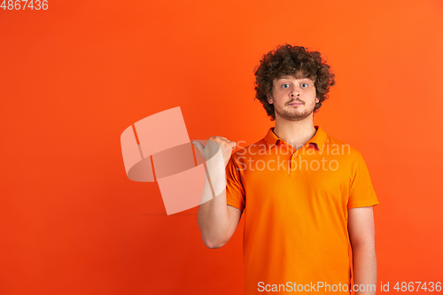 Image of Caucasian young man\'s monochrome portrait on orange studio background