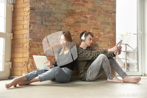 Image of Attractive young couple using devices together, tablet, laptop, smartphone, headphones wireless. Gadgets and technologies connecting people all around the world