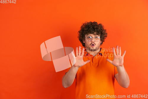 Image of Caucasian young man\'s monochrome portrait on orange studio background