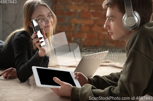 Image of Attractive young couple using devices together, tablet, laptop, smartphone, headphones wireless. Gadgets and technologies connecting people all around the world