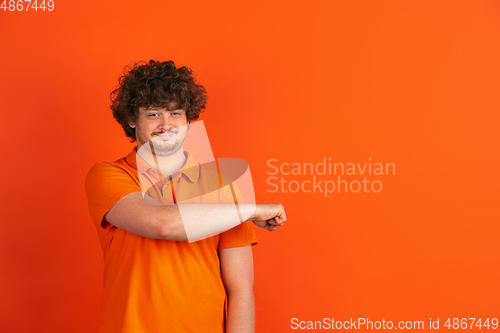 Image of Caucasian young man\'s monochrome portrait on orange studio background