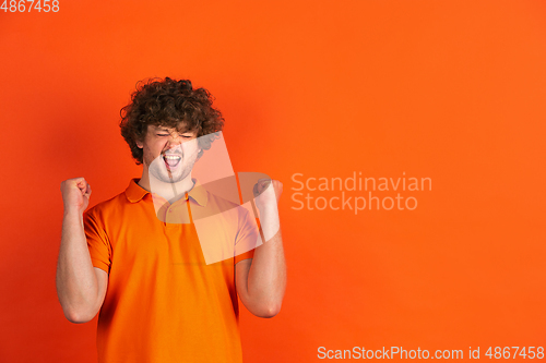 Image of Caucasian young man\'s monochrome portrait on orange studio background
