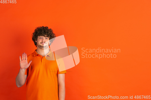 Image of Caucasian young man\'s monochrome portrait on orange studio background