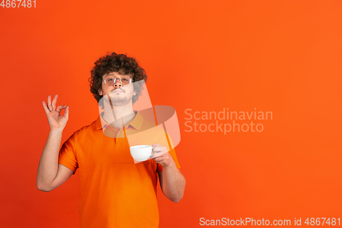 Image of Caucasian young man\'s monochrome portrait on orange studio background
