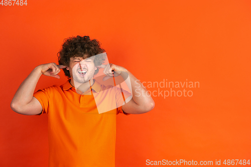 Image of Caucasian young man\'s monochrome portrait on orange studio background