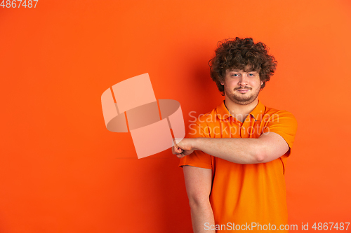 Image of Caucasian young man\'s monochrome portrait on orange studio background
