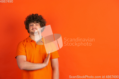 Image of Caucasian young man\'s monochrome portrait on orange studio background