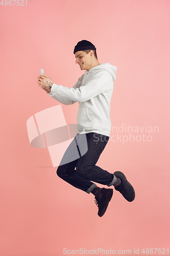 Image of Caucasian young man\'s modern portrait on pink studio background in high jump