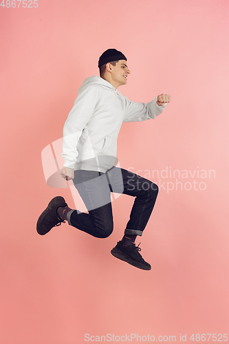 Image of Caucasian young man\'s modern portrait on pink studio background in high jump
