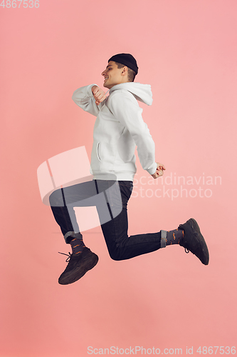 Image of Caucasian young man\'s modern portrait on pink studio background in high jump