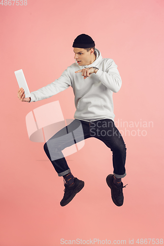 Image of Caucasian young man\'s modern portrait on pink studio background in high jump