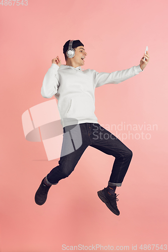 Image of Caucasian young man\'s modern portrait on pink studio background in high jump