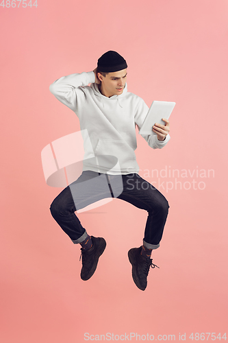 Image of Caucasian young man\'s modern portrait on pink studio background in high jump