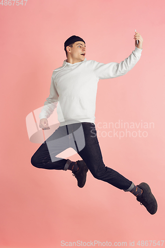 Image of Caucasian young man\'s modern portrait on pink studio background in high jump