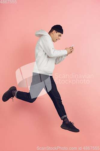 Image of Caucasian young man\'s modern portrait on pink studio background in high jump