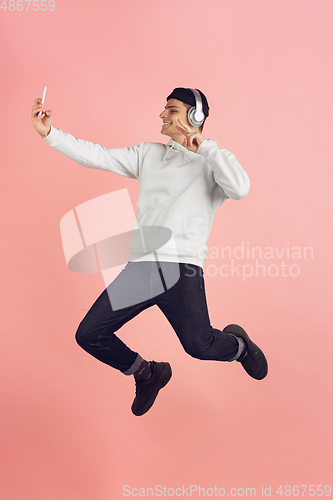 Image of Caucasian young man\'s modern portrait on pink studio background in high jump