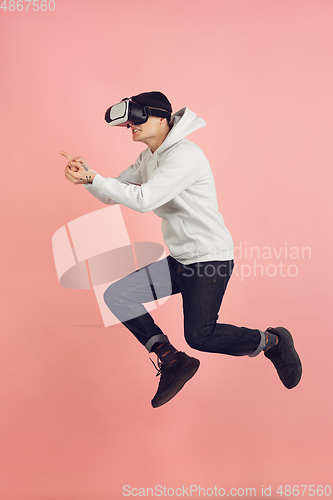 Image of Caucasian young man\'s modern portrait on pink studio background in high jump