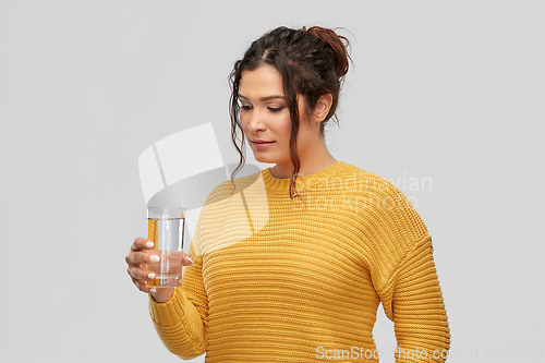 Image of smiling young woman with water in glass