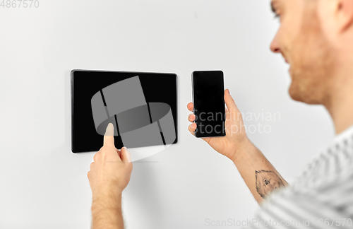 Image of man with smartphone and tablet pc at smart home